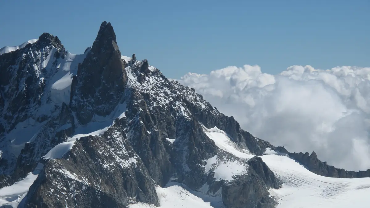 The rock spire of the Dent du Géant above the glacier, with a sea of clouds