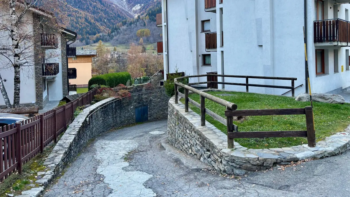 The ramp going down to the underground garage, between the lawn and the stone wall.
