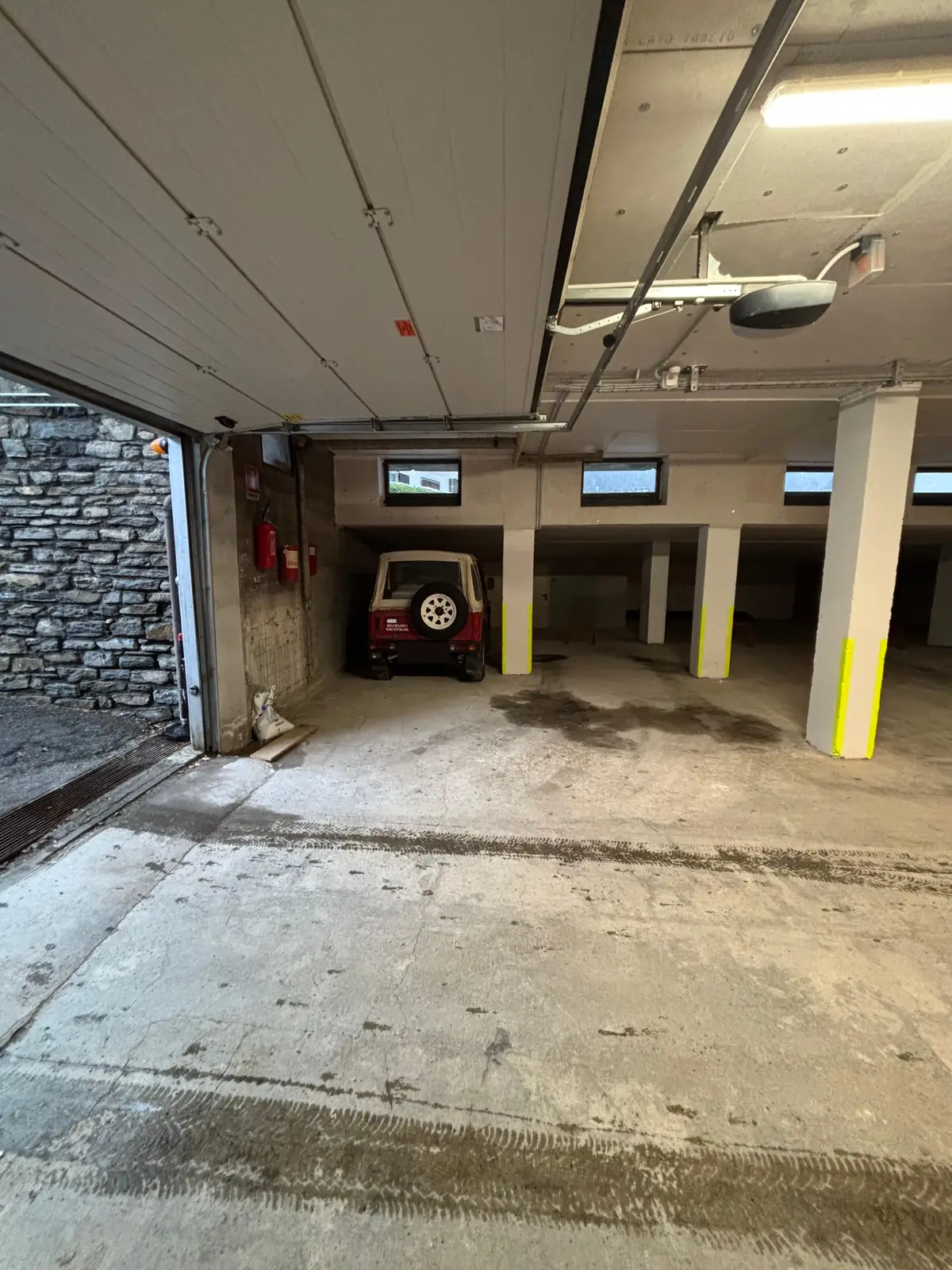 The underground garage seen from the open door, with the parking spots and pillars.