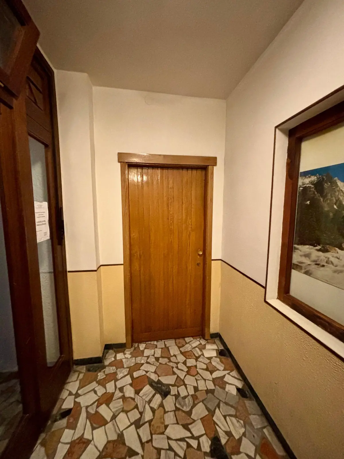 The ground-floor entrance, with a glass door on the left and a wooden door at the end.