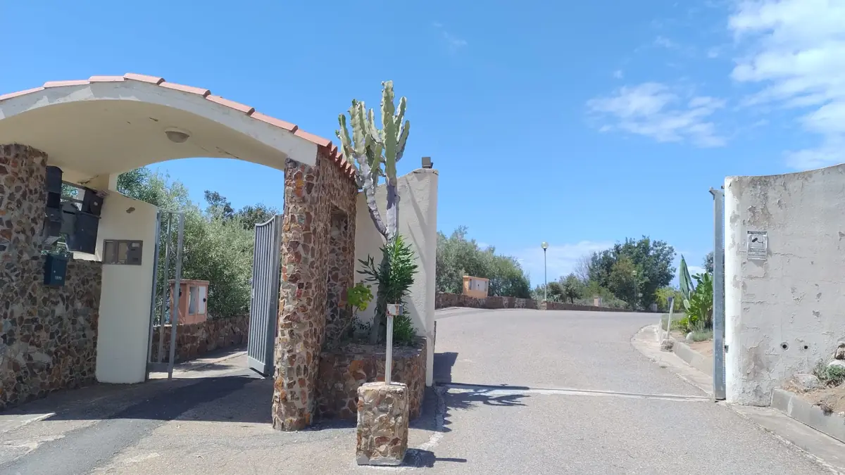 The residence entrance with the stone arch; the road continues to the right.