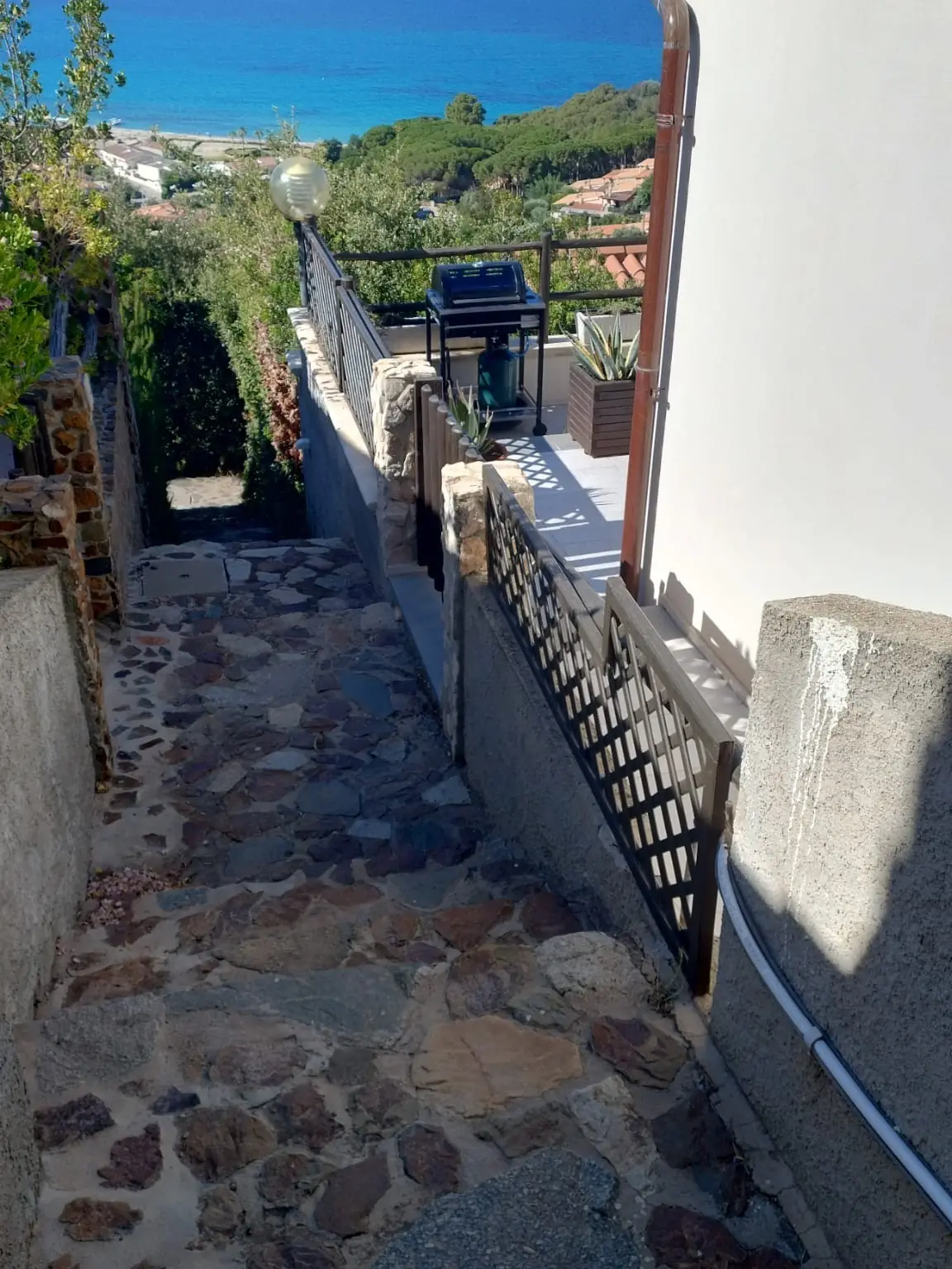 The stone path to the terrace, wooden gates on the right and the sea beyond.