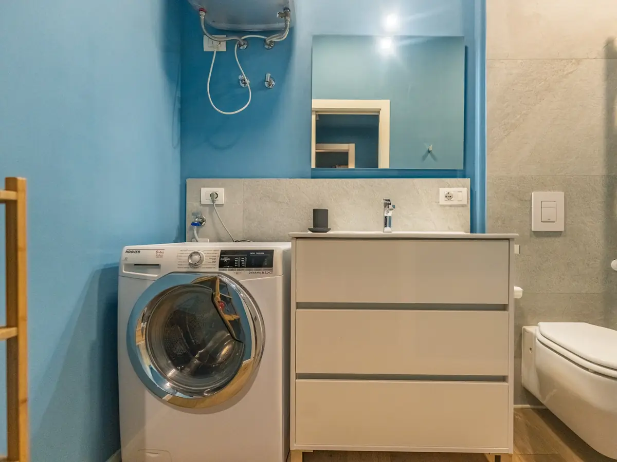 Bathroom with washing machine, white vanity unit and mirror